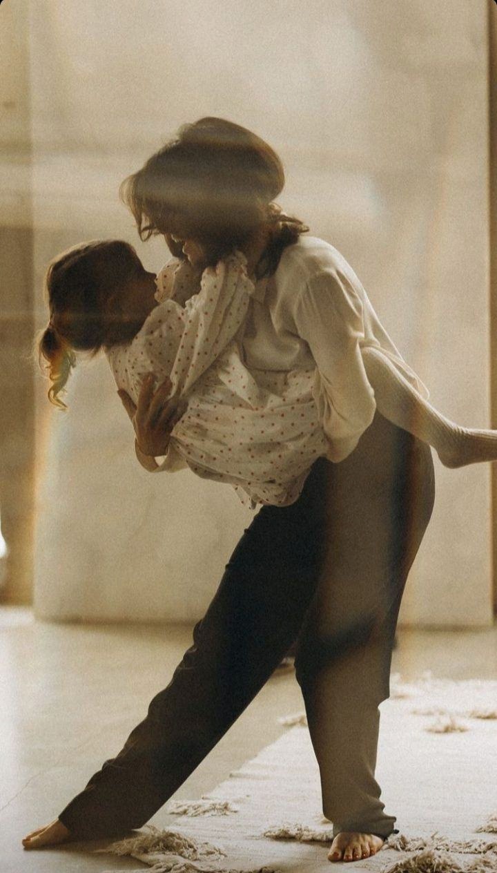 A mother carrying her daughter in warm window light